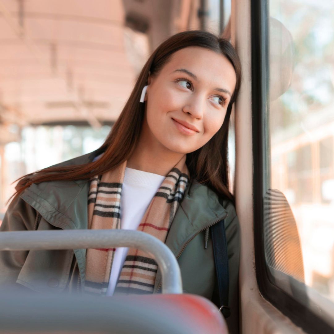 Ragazza su un pullman che guarda sorridente fuori dal finestrino