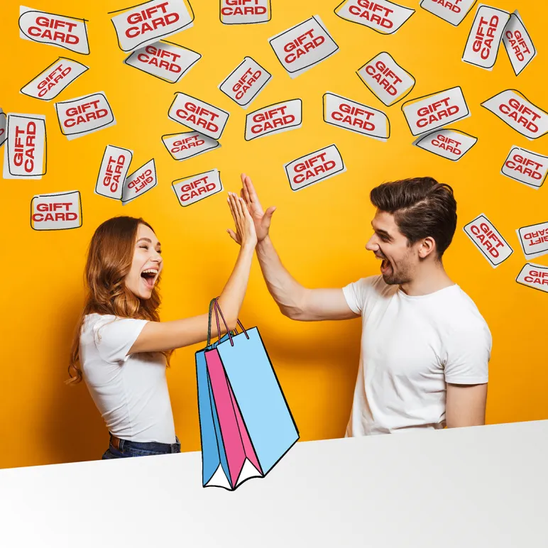 Due ragazzi esultano tra piogge di gift card, con borse da shopping in primo piano su sfondo giallo.
